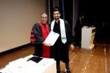 Daniel Yamin in a graduation gown receiving his MSc certificate on stage at Tel Aviv University