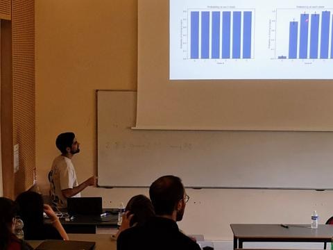 Daniel Yamin presenting bar-chart results of a behavioral model to a seated audience